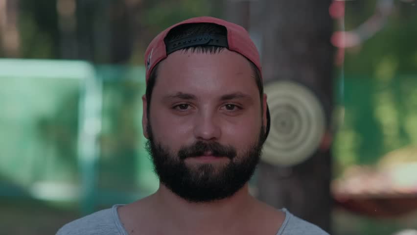portrait of a guy with a beard in a red cap, turned backwards visor