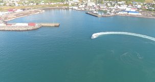 HUSAVÍK, ICELAND – SEPTEMBER 2016 : Aerial shot of speedboat in Husavík Bay on a beautiful day