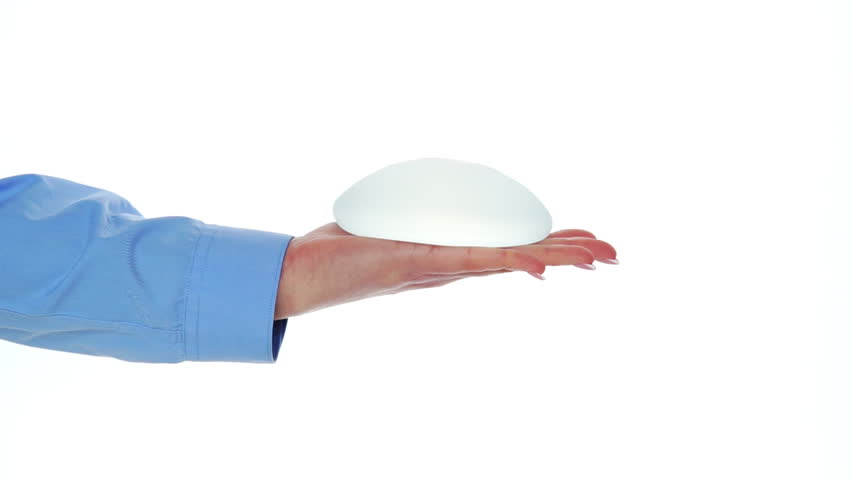 Breast implants in hand on white background. Breast augmentation. Royalty-Free Stock Footage #3450391323