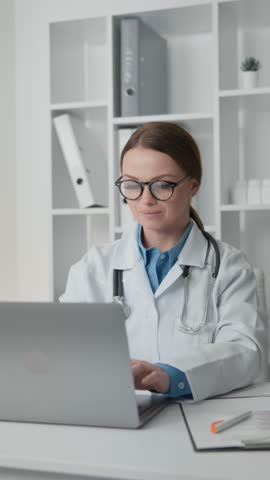 Female doctor with stethoscope working focused on laptop, analyzing medical data and developing personalized treatment plans for each patient in clinic. Doctor in white coat and glasses Royalty-Free Stock Footage #3450406475