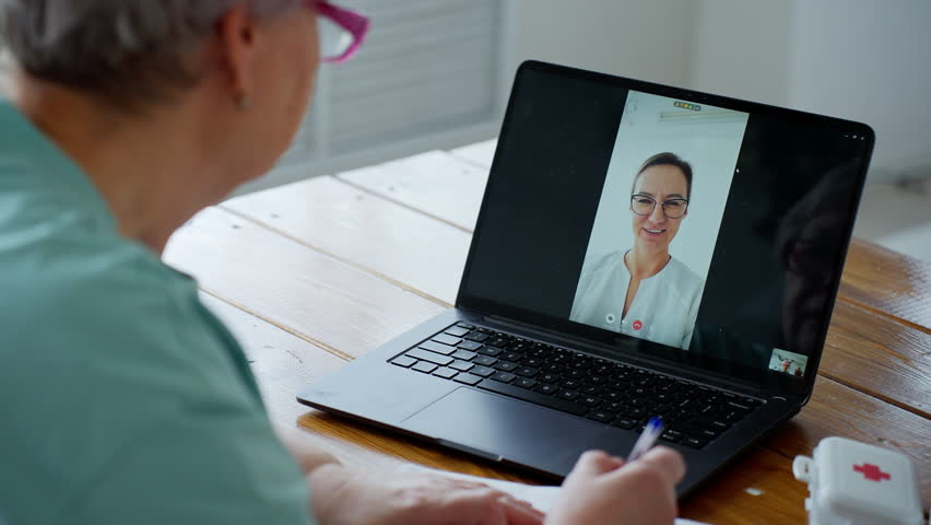 The elderly woman consults with her doctor online using her laptop