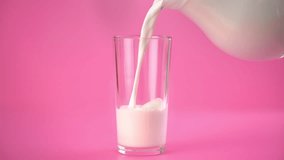 Glass and jug with milk in pink background, person pouring vegan plant milk, isolated studio shot. Organic eco-friendly farm produce of milk, healthy lifestyle and tasty beverage, milk in daily diet - Powered by Shutterstock - Get 15% off with code: PIKWIZARD15