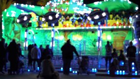 Night scenery atmosphere with colourful illumination motion of carousel in amusement park and background of Ferris wheel. Blurred video.