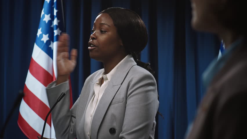 Medium shot of young African American female politician having confrontation with anonymous opponent at debate, in front of USA flag, blaming and suggesting solutions to high inflation crisis Royalty-Free Stock Footage #3450571805