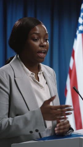 Medium close-up vertical footage of young black female candidate running for US Senate or Congress participating in debate during election, speaking candidly on social problems, arguing with opponent