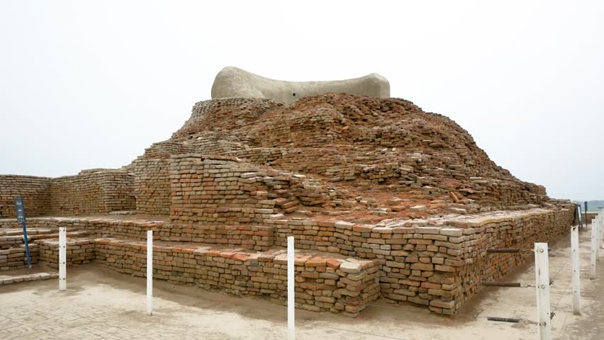 Ancient stupa remains, brick construction, fenced historical site, cloudy sky. Mohenjho daro, Sindh, Pakistan.