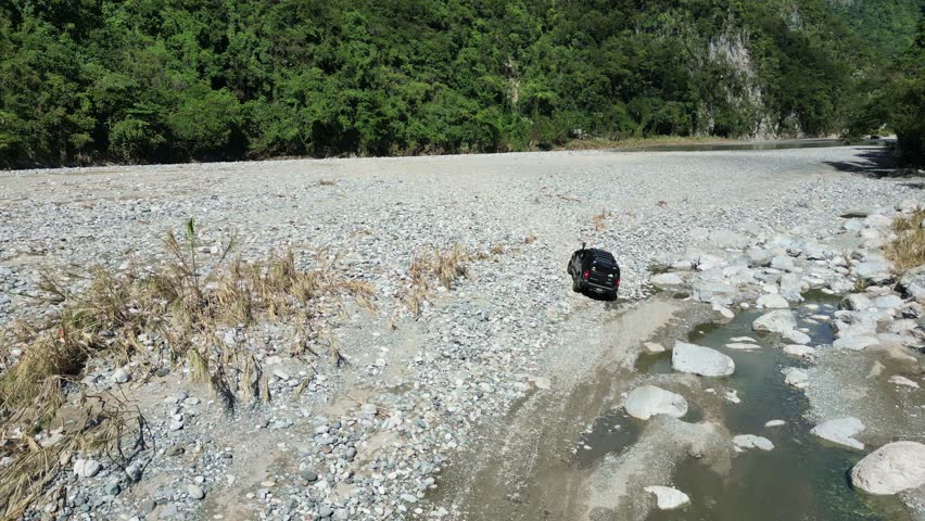 Off-road vehicles 4x4 on riverbank, Muchas Aguas in Dominican Republic. Aerial forward at low altitude tracking (part 3)