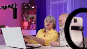 creative old man together with an elderly woman having fun in retirement writing a blog in a modern room