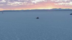 Vehicle and people in Bonneville Salt Flats at sunset, Utah. Aerial drone orbiting and space for copy