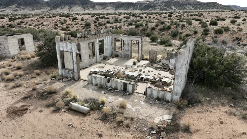 abandoned building concrete structures destroyed by the cartel in the high desert of southern California on an overcast day with an apocalyptical mood AERIAL TRUCKING PAN 60fps