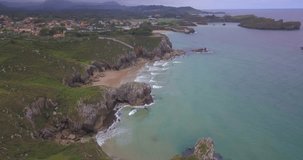 Aerial view of secluded beach and cliffs near village. Coastal landscape with rocky shoreline