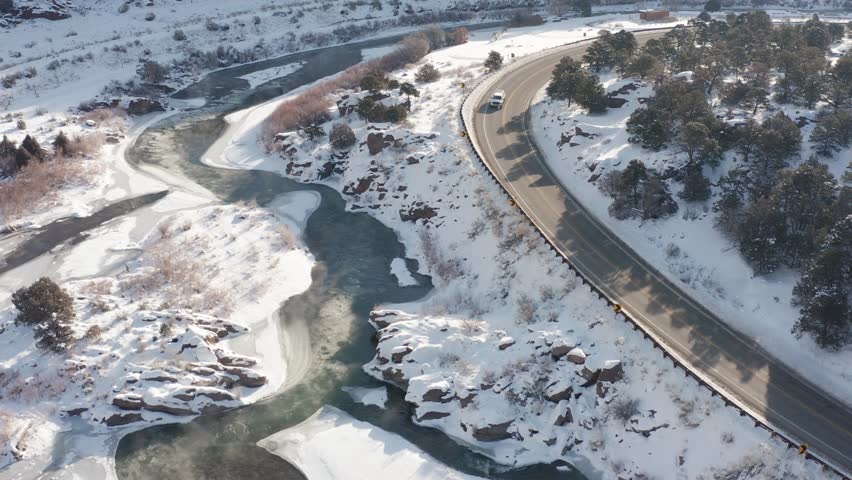 Early morning snowy winter river scene from above along side a road or highway