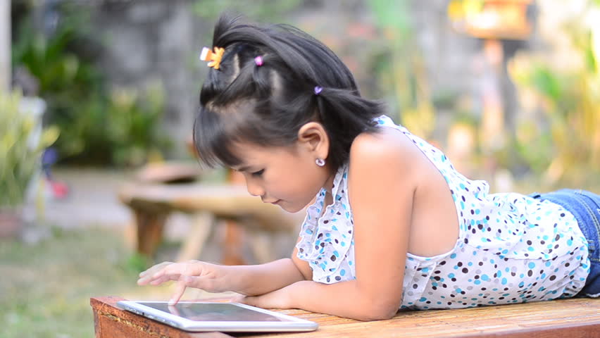 Asian little girl playing a game on computer tablet