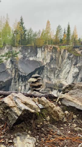 Close-up of a stone tower in a nature park. Marble canyon with coniferous and deciduous trees on the rocks. Autumn landscape.