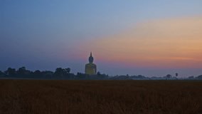 colorful sky in sunrise at golden big buddha a popular landmark in Thailand..video 4K Nature video High quality footage for worship and travel concept..rice field background..