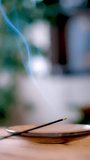 Vertical video. A scented incense and meditation stick lies on a table in the room and smoke comes from it. Background or screen saver on mobile devices.
