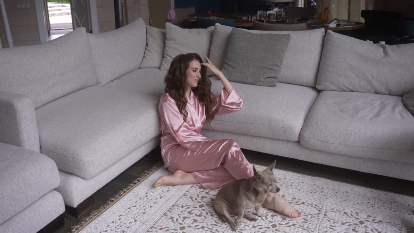 A woman sits on a comfortable couch with a cat in a house