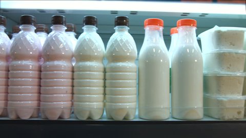 Sour-milk products in the supermarket.
Horizontal pan.
The camera moves along the shelf on which are bottles of milk and dairy products.