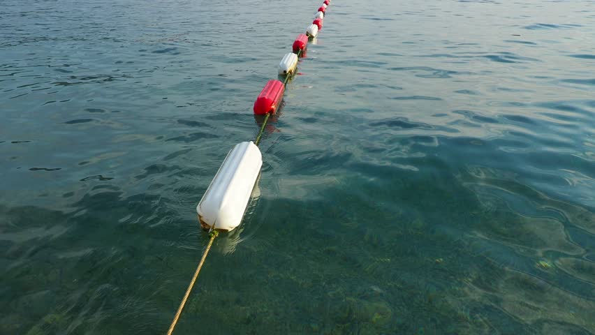 Buoy swim area marker. Visible channel marker coated with durable white and marine red enamel for increased durability. Assembling barrier and swim areas. Buoys on the water, Adriatic Sea, Montenegro. Royalty-Free Stock Footage #3451012933