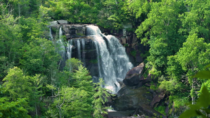 Whitewater Falls with falling down clear water from rocky boulders between green lush woods in Nantahala National Forest, North Carolina, USA