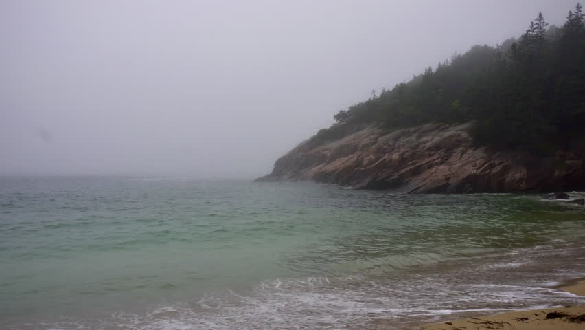 Crashing waves on Sand Beach in Acadia National Park, Maine. Surrounded by cliffs, this small stretch of coast is the largest sandy beach in Acadia. Rough surf on foggy, stormy day. 