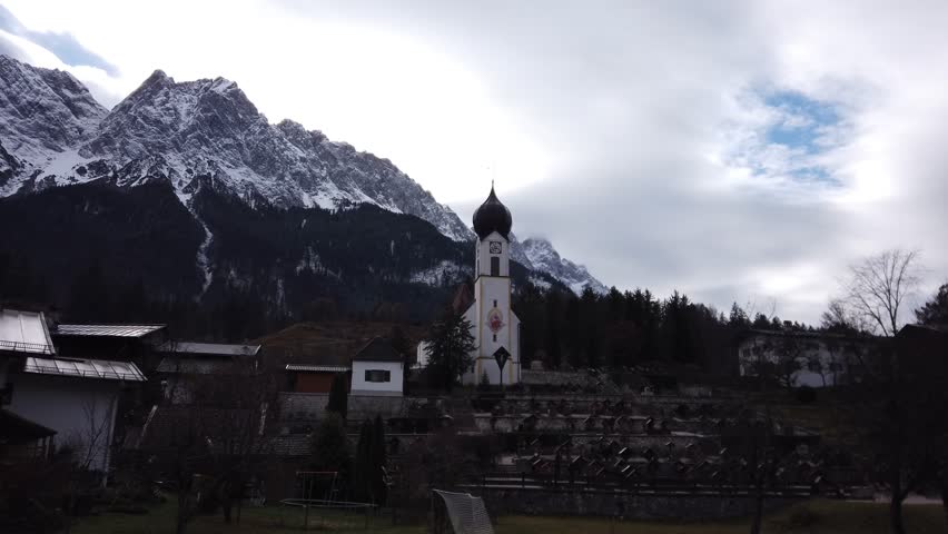 DOLLY SHOT - The parish church of St. Johannes der Taufer (John the Baptist) with the Mount Waxensteine in the background, Grainau, Garmisch-Partenkirchen, Bavaria, Germany.