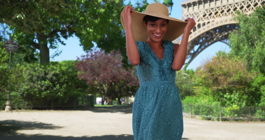 Playful mixed race woman traveling in Paris, France dances with joy in front of the Eiffel Tower. Beautiful millennial female enjoying her vacation in France. 4k