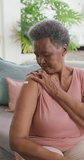 Vertical video of portrait of happy senior african american woman alone at home. senior healthcare and medical physiotherapy treatment.