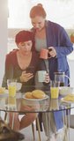 Vertical video of happy caucasian lesbian couple having breakfast at home. spending time together at home.