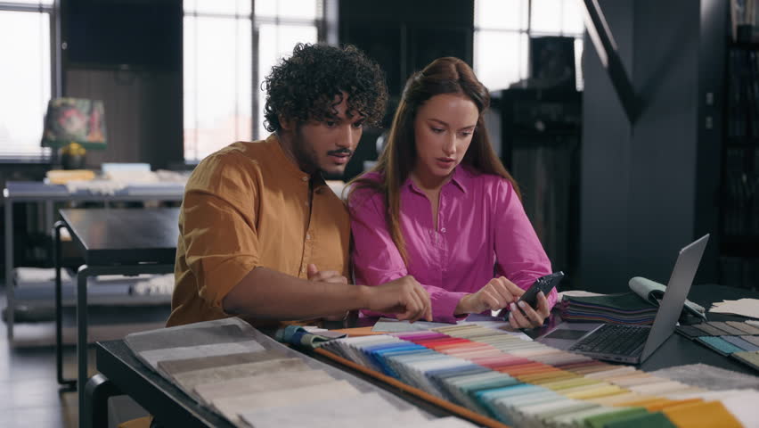 Multiracial couple creative designers work in modern office studio Arabian Indian man Caucasian woman using phone choosing perfect sample of material color tone for new house interior design project Royalty-Free Stock Footage #3451342143