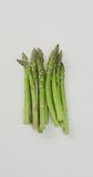 Vertical video of fresh stalks of asparagus on white background. fresh and organic vegetable produce.