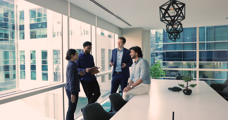 Four young and ambitious successful office employees, multinational staff lead pleasant conversation standing in modern conference room, take part in informal meeting, share creative idea and solution Royalty-Free Stock Footage #3451371881