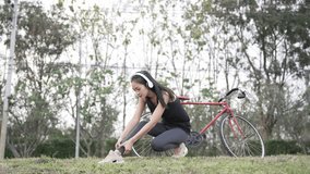 Asian woman happily rides a bicycle to exercise in the park with a backpack on her back. 4K video