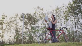 Asian woman happily rides a bicycle to exercise in the park with a backpack on her back. 4K video