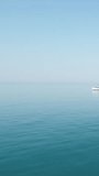 Aerial yacht on calm sea. Luxury cruise trip. View from above of white boat on deep blue water. Aerial view of rich yacht sailing sea. Summer journey on luxury ship. Vertical video