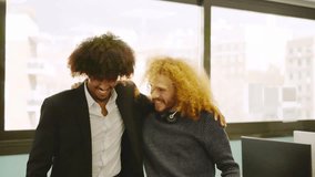 Coworkers with curly hair embracing in the office