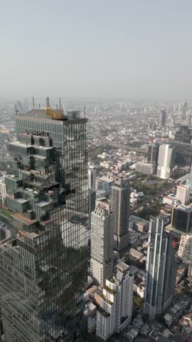 A close-up view of the tallest skyscraper in Bangkok with the panoramic cityscape in the background, showcasing the impressive architecture and vibrant urban atmosphere. Bangkok, Thailand.