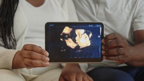 Close up of hands of unrecognizable black couple showing ultrasound picture of their baby on digital tablet - Powered by Shutterstock - Get 15% off with code: PIKWIZARD15