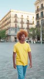 Vertical video of a young African-American man happy and smiling as he walking down a city street.     Slow motion video of a young afro man walking happy on the street looking at the buildings. 