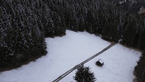 Small Hut in the Mountains in Austria in winter with snow covered pine forest. Aerial drone flight above forest 4K 30 fps video