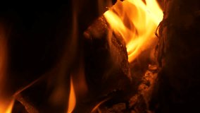 Burning firewood, with vibrant flames and embers, extreme close-up view.