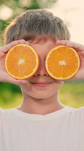Fruit vitamins for boy from garden. Boy child plays with fresh juicy oranges. Cute child is holding orange slices like orange glasses. Concept of healthy eating for child. Happy family. Healthy food Royalty-Free Stock Footage #3451917225