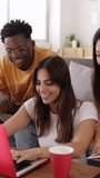 Young group of diverse students studying together using laptop at home. College multiracial people working on university group assignment homework project in modern apartment. Vertical HD video.