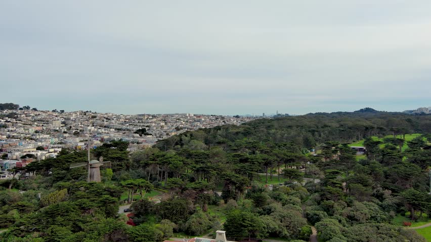 aerial footage of Golden Gate Park with people playing soccer on a soccer field, lush green trees, plants and grass and homes along the hillside in San Francisco California USA