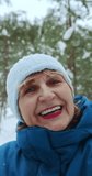 The view from the smartphone camera, an elderly woman communicates via video call and tells how good it is in the winter snow forest. A happy retired woman calls her grandchildren. High quality 4k