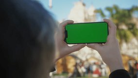 Young man holding phone chroma key screen on the street close-up. Male with green screen on smart phone swiping . 