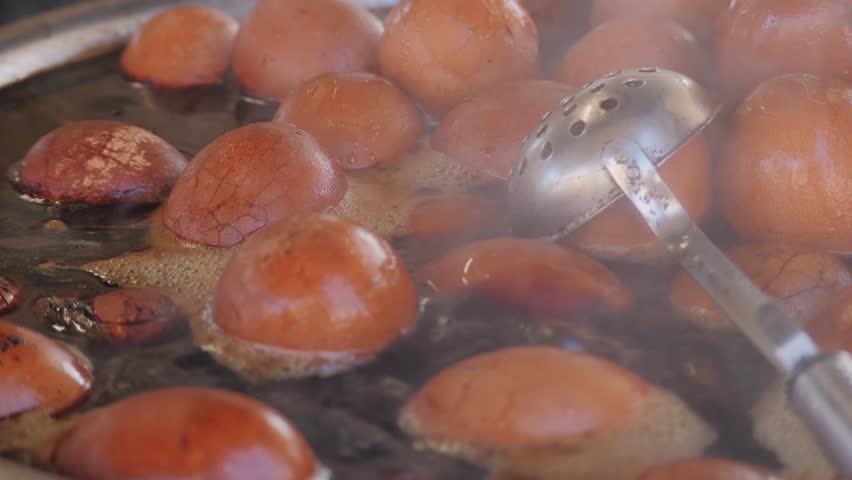 Chinese century eggs or tea egg in boiling water close-up. Chinese egg-based culinary dish made by preserving duck, chicken, or quail eggs in a mixture of clay, ash, salt, quicklime, and rice hulls Royalty-Free Stock Footage #3451950527