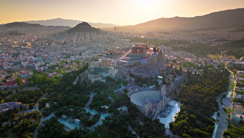 Aerial view of the ancient citadel Acropolis of Athens, historical landmark. Sunset over temple complex on rocky hilltop, landmark temple ruins on archaeological site of Parthenon and Amphitheater.
