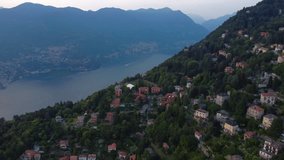 Aerial drone video of houses on a hill with Lake Como and mountains in the background