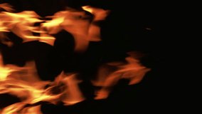 Vertical video. Burning fire. Flame texture. Yellow orange color glowing campfire hot blaze sparks motion on black dark night copy space background.